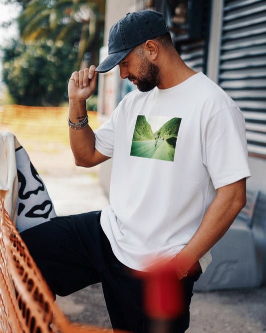 Manuel Store white 100% cotton t-shirt with a printed graphic of a skateboarder on a road between mountains.