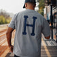 Manuel Store grey cotton t-shirt with large blue 'H' logo on back. Classic fit, short sleeves.