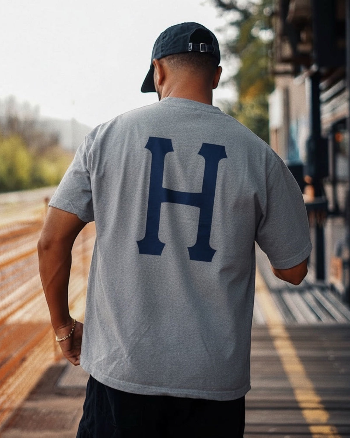 Manuel Store grey cotton t-shirt with large blue 'H' logo on back. Classic fit, short sleeves.