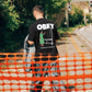 Manuel Store black 100% cotton t-shirt with OBEY graphic and "The Medium is the Message" text.