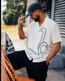 Manuel Store white short-sleeve cotton-linen blend shirt with black swan graphic print and button closure.